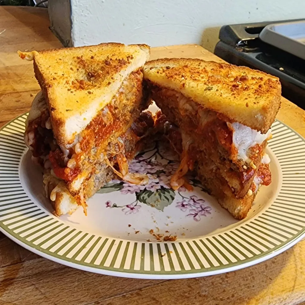 The Meatball Club:  A double-decker meatball sandwich on toasted white bread, teeming with tasty sauce & melted Gruyere and Swiss cheese.  (Cut open diagonally.)
